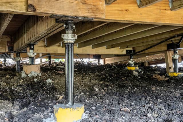 Quality Foundation Repair Austin installing adjustable steel jacks to stabilize a crawl space foundation and wooden joists.