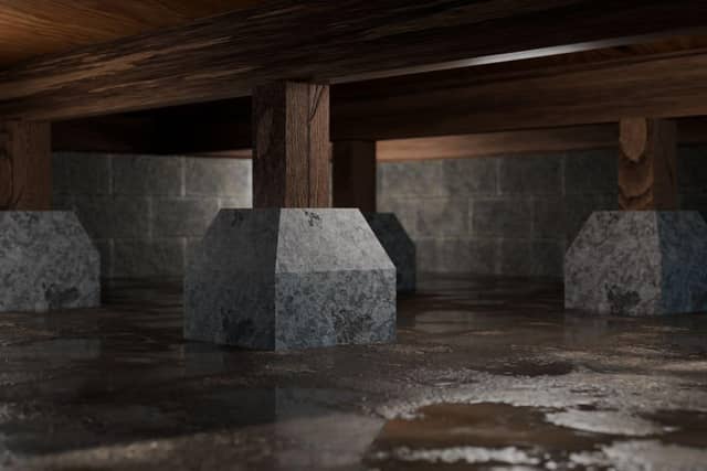 Quality Foundation Repair Austin inspecting a wet crawl space with standing water around concrete support piers.