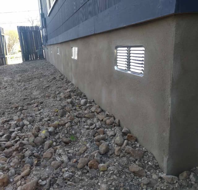 Quality Foundation Repair Austin installing crawl space vent covers on an exterior foundation wall.