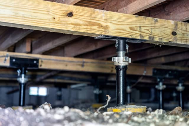 Quality Foundation Repair Austin stabilizing a crawl space with adjustable steel jacks supporting wooden floor joists.