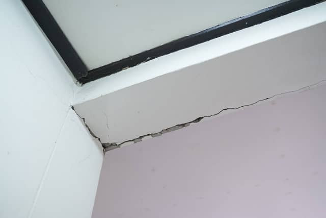 Quality Foundation Repair Austin inspecting a significant crack where an interior wall meets the ceiling, indicating structur