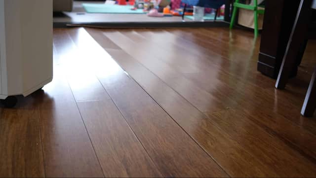 Quality Foundation Repair Austin inspecting uneven floors with visible floor sagging and gaps in wood floorboards.