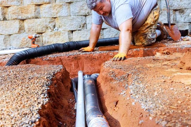Quality Foundation Repair Austin installing drainage pipes in an excavated trench for crawl space moisture control.