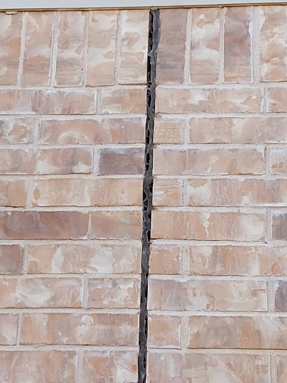 A crack running through the brick veneer of a Central Texas home, a common sign of slab movement.